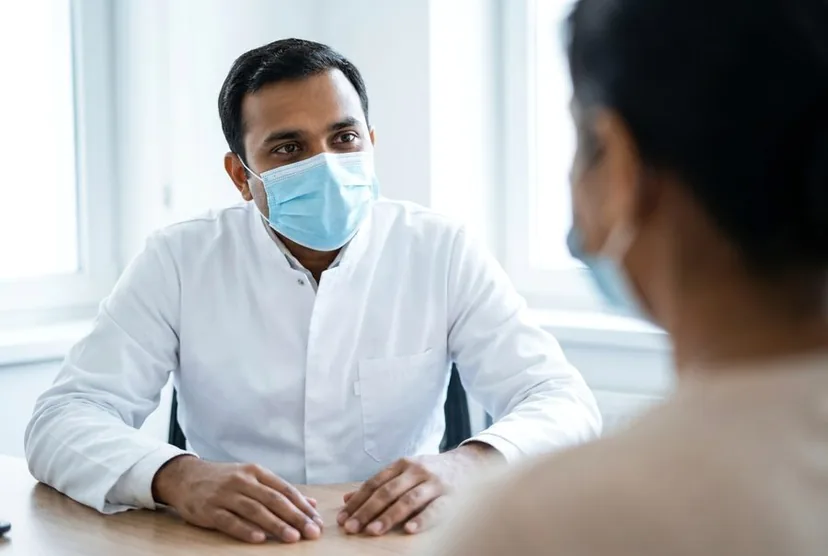 A doctor listening to a patient across a desk