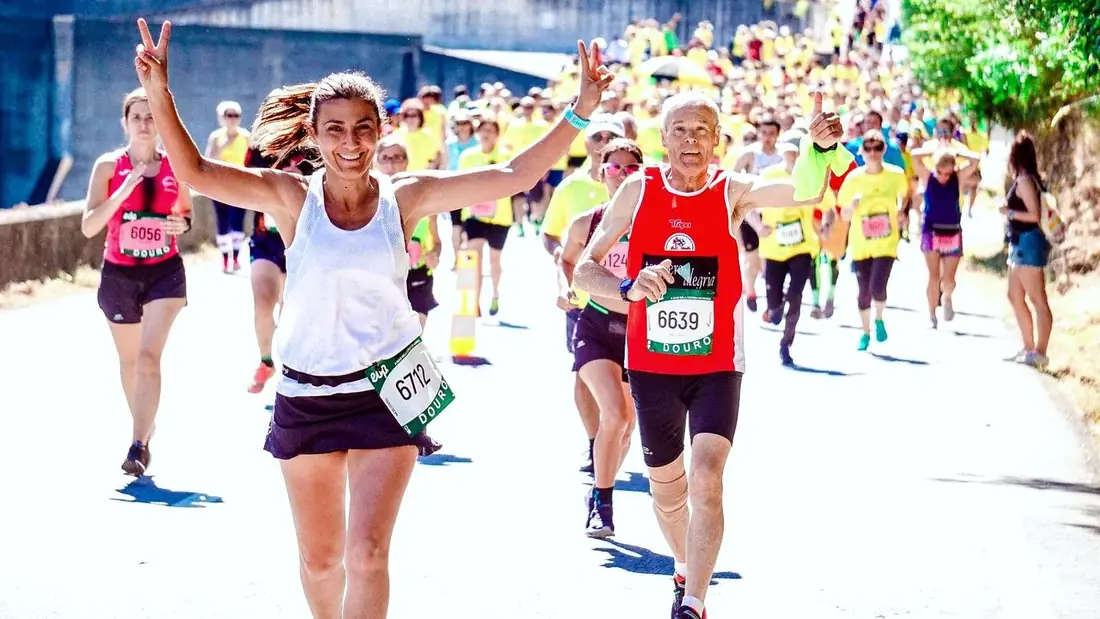 Runners crossing a marathon finish line with their arms raised in celebration